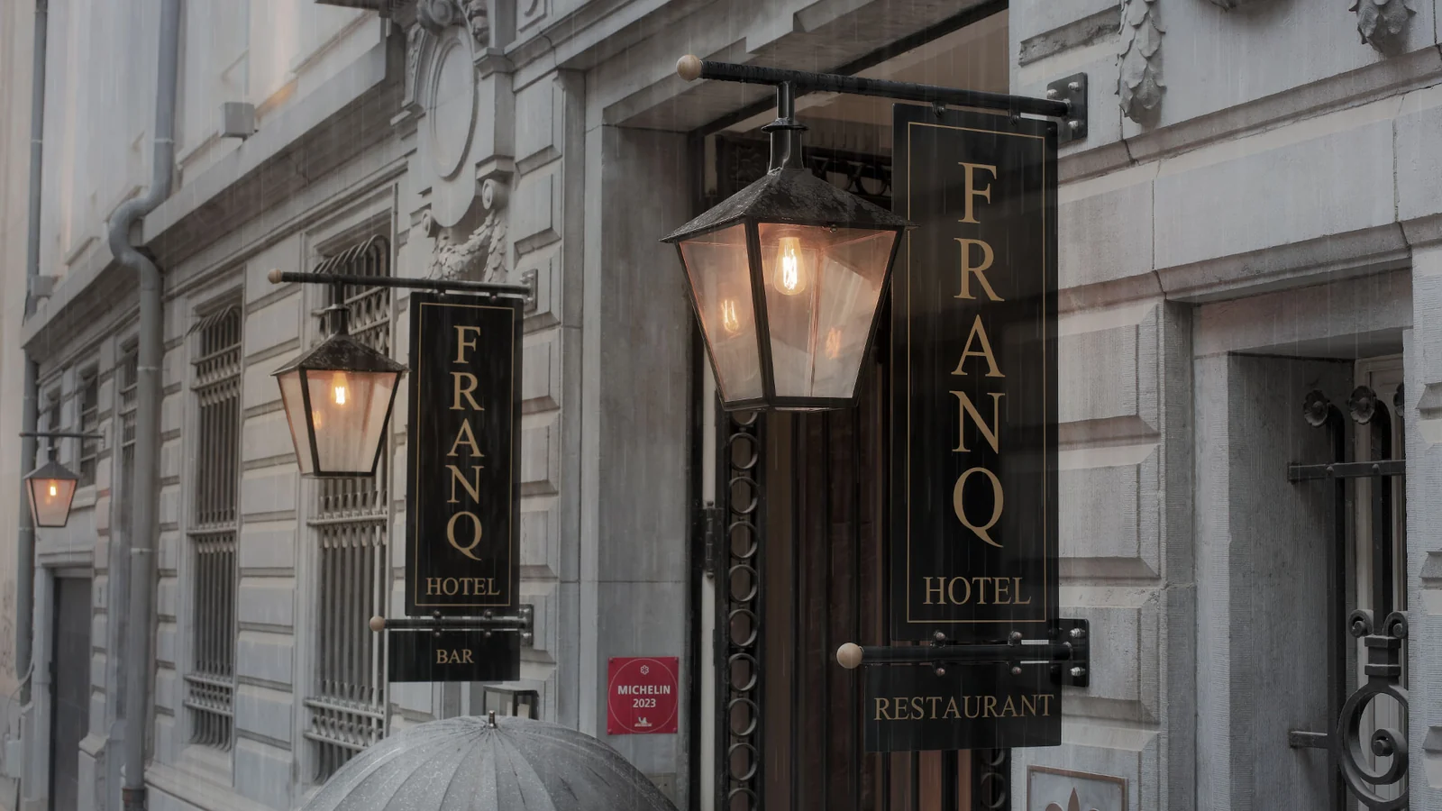 Verlichte lantaarns met gevelreclame aan de gevel van Hotel Franq in Antwerpen.