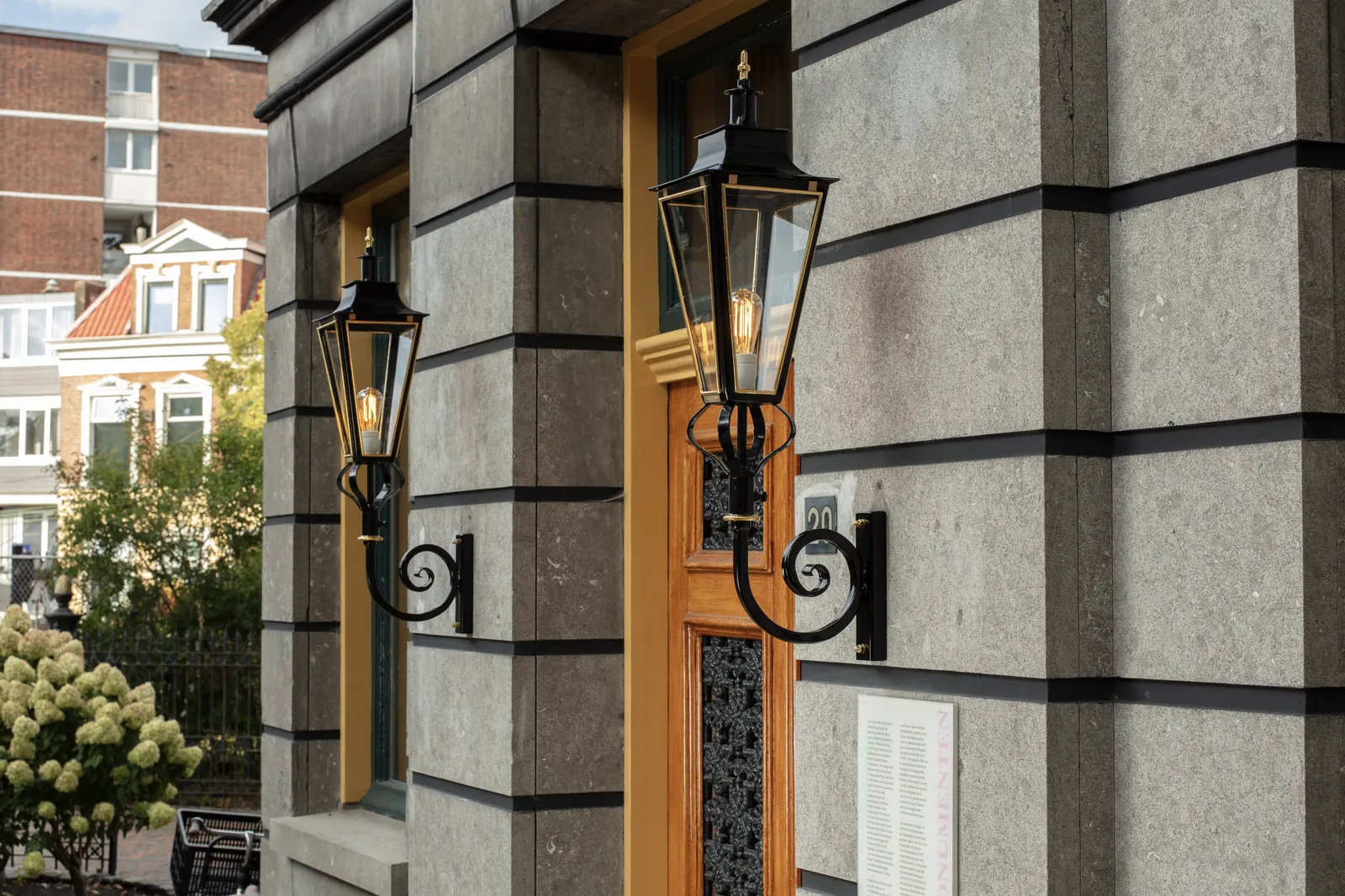 Lantaarns met goudkleurige details bij een stenen gevel en houten deuren.