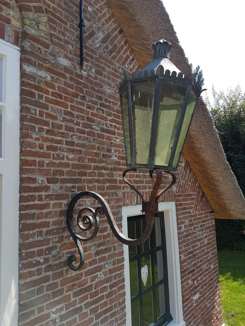 De lantaarn in Loosdrecht voor revisie, met verweerde afwerking en roest aan de muurarm.